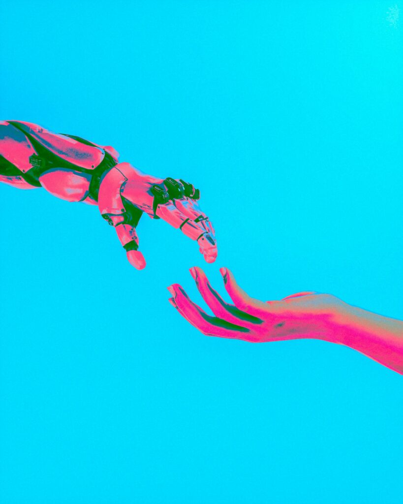 Robotic hand reaches toward a human hand against a vivid blue background, symbolizing human–machine connection.