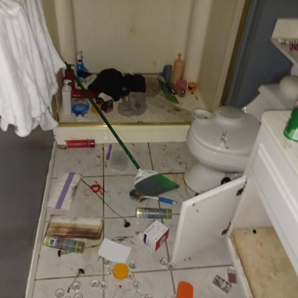 Messy bathroom with scattered toiletries, bottles, toothpaste, and orange sponges on the floorNet cluttered bathroom counter and floor with cleaning products and miscellaneous items